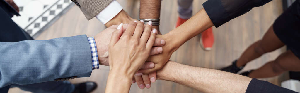 Top view of group multi ethnic coworkers stacked hands together as concept of corporate unity
